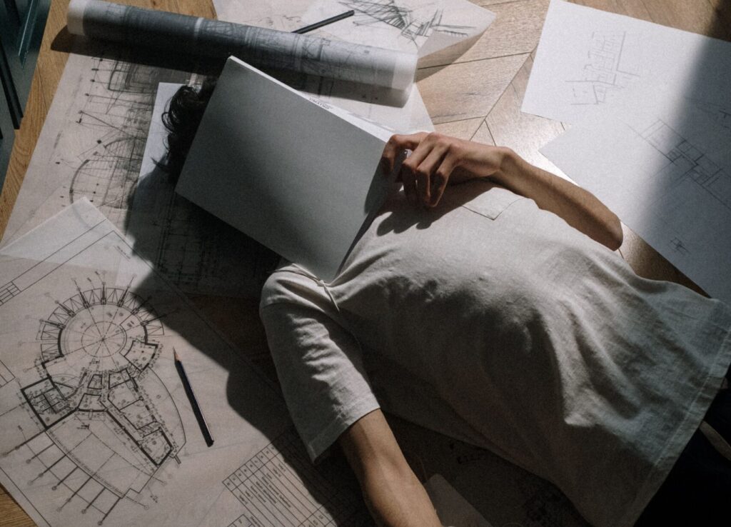 A tired architect lying among their paperwork
